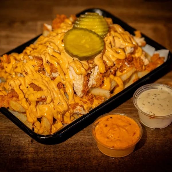 Flamin Feathers' loaded fries with fried chicken, cheese sauce, and pickles, with two dipping sauces.