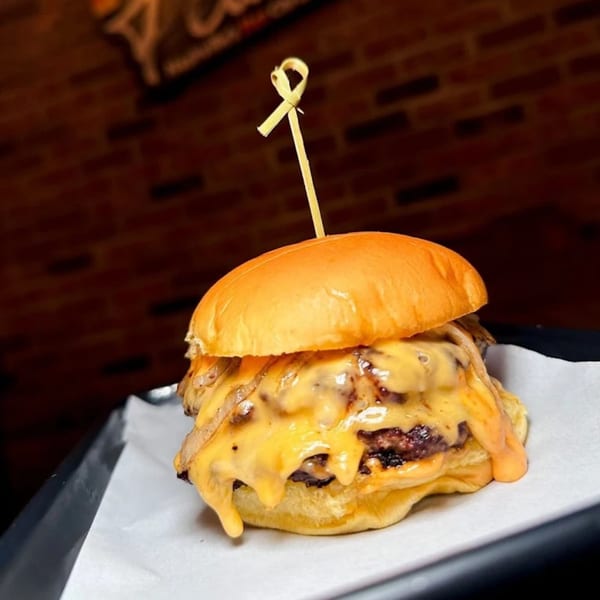 A Flamin Feathers burger with melted cheese and caramelized onions on a brioche bun.