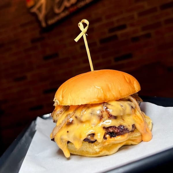 A Flamin Feathers double cheeseburger with melted cheese and caramelized onions on a brioche bun.