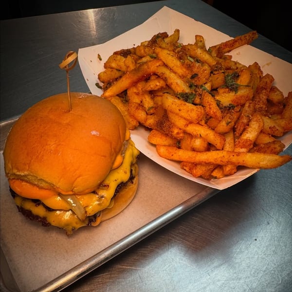 A Flamin Feathers double cheeseburger with melted cheese and onions, served with seasoned fries.