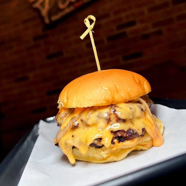 A Flamin Feathers burger with melted cheese and caramelized onions on a brioche bun.